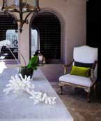 The green and olive cushions work with the green orchid leaves to accent the pristine white of this interior